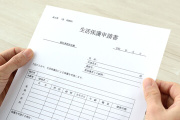 Obraz premium 生活保護申請書を持つ人物の手元