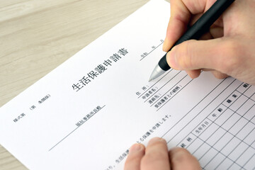 生活保護申請書に記入する人物の手元