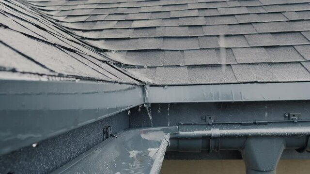 Jets of rain drain into the drainage system on the roof of the house