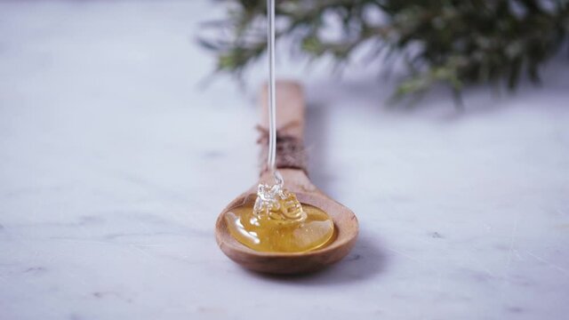 Flow of honey. Golden, yellow, raw honey is dropping from honey dipper on wood tablespoon. Healthy sweet ingredient for natural cosmetics, pastry and breakfast.