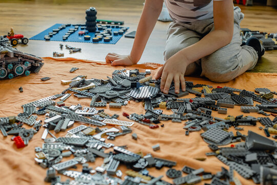 A Blond Boy Of Nine Years Old Collects A Large Lego Set Of The Millennium Falcon In His Room. Based On The Film Star Wars.