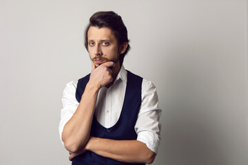 serious portrait of a man in a vest in a white shirt on a white background in the studio