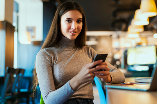 Business woman sitting at table working on project. Young woman using digital devices for work. Girl communicates with friends, clients through social networks using messenger smartphone app