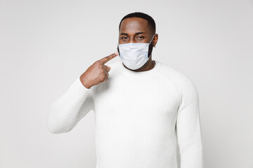 Young african american man in basic sweater pointing index finger on sterile face mask to safe from coronavirus virus covid-19 during pandemic quarantine isolated on white background studio portrait.