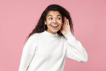 Young african american woman 20s curly hair in white knitted sweater try to hear you overhear...