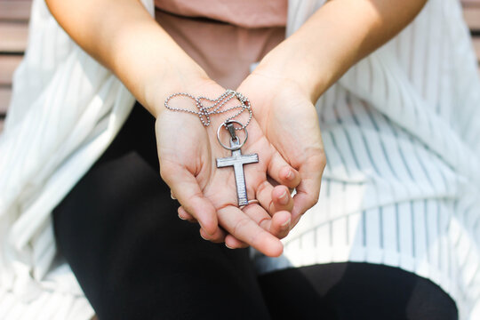 Christian Woman's Hand Holding A Cross Necklace