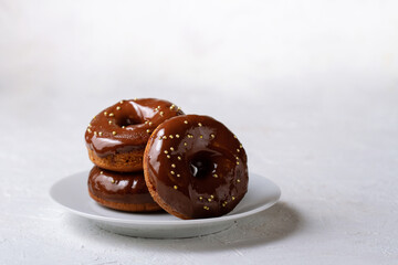Three chocolate donuts on a white plate, free space.
