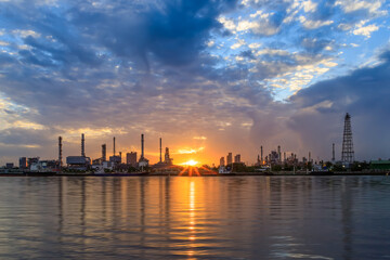 Oil and gas refinery plant factory with refection on river at sunrise. petrochemical and energy industry concept.