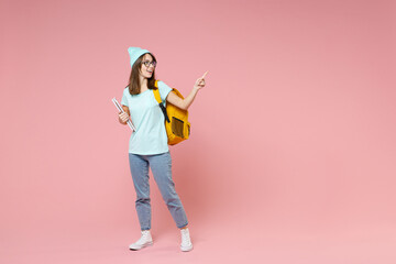 Full length of excited young woman student in blue t-shirt hat glasses backpack hold notebooks...