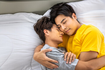 Happy Asian homosexual gay men male couple lying and embracing on bed, sleeping together. LGBT and sexual diversity concept.