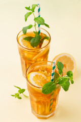 Traditional homemade iced tea with lemon, mint and ice in tall glasses. Summer cold drink concept.