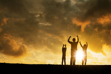 Fototapeta premium Two children chering with their father on hill peak