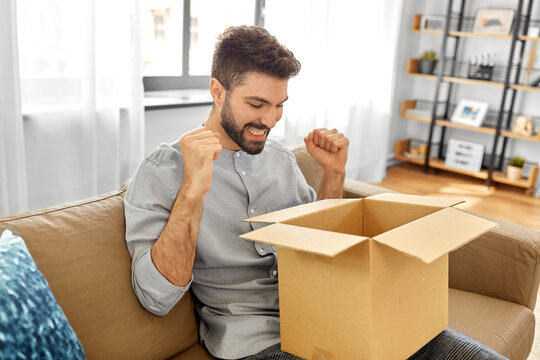 mail delivery, shipment and people concept - happy smiling man with open parcel box at home