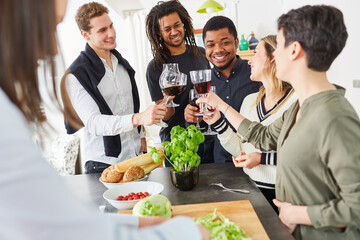 Glückliche Freunde stoßen vor Essen mit einem Glas Wein in der Küche an