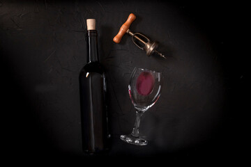 Wine tasting, top shot on a black background, with a cork, corkscrew, and a wine bottle