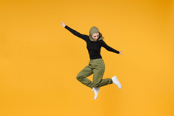 Fototapeta na wymiar Full length of cheerful young arabian muslim woman wearing hijab black green clothes jumping spreading hands isolated on yellow color background studio portrait. People religious lifestyle concept.