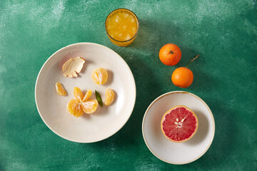 food, healthy eating and fruits concept - still life with mandarins, grapefruit and glass of juice on green background