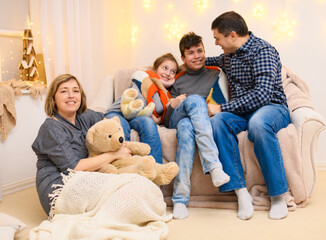 portrait of a family sitting on a sofa at home, four people having fun together