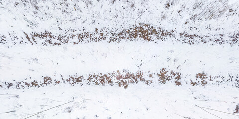 panorama view from above on texture of snow covered gravel dirt road in the forest