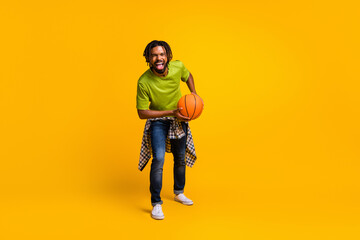 Fototapeta na wymiar Photo portrait full body view of laughing guy holding ball isolated on vivid yellow colored background