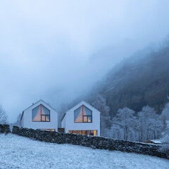 Modern white house with large windows surronded by nature, snow and fog