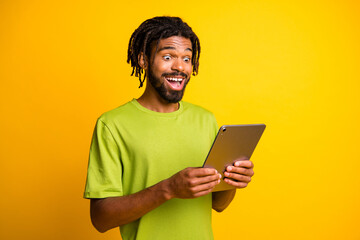 Photo of young man use modern device tablet read surprised excited news information isolated over yellow color background