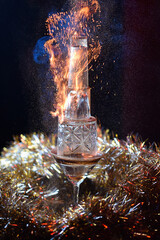 alcoholic cocktail from sambuca with fire from a tower of glasses on a dark background with a Christmas tree