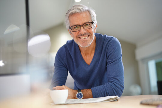 Senior man at home relaxing and reading newspaper