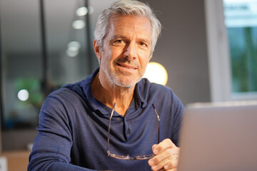 Portrait of senior man with grey hair connected with laptop