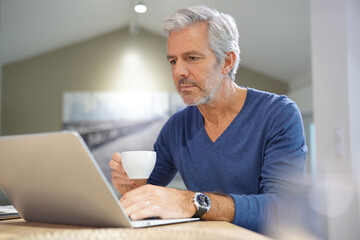 Fototapeta na wymiar Portrait of senior man at home working on laptop