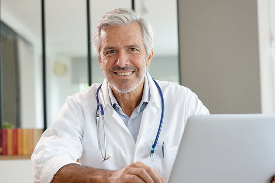Portrait of attractive mature doctor working in office