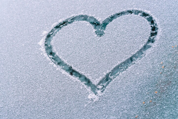 A heart painted on a frozen car window in winter