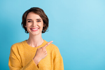Fototapeta premium Photo portrait of happy female student wearing jumper pointing at empty space smiling cheerfully isolated on vibrant blue color background