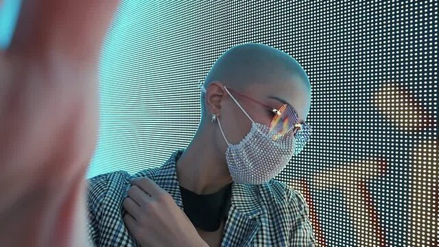 Cinematic image of a beautiful young woman posing against a led panel. Concept about lifestyle and the 2021 cyberpunk fashion look