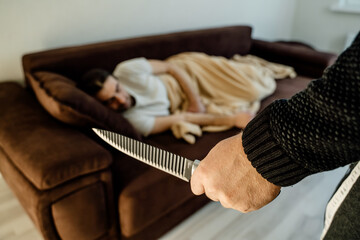 Crime Concept. human hands with knife ready to attack man who is sleeping in bed at home in the...
