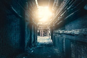 Dark dirty corridor in abandoned industrial factory with light in end, horror concept.