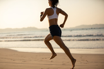 Fototapeta na wymiar Young fitness woman running at sunrise beach