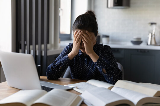 Upset millennial Indian female student feel distressed exhausted with homework assignment or preparation. Unhappy young ethnic woman stressed overwhelmed with amount of work. Deadline concept.