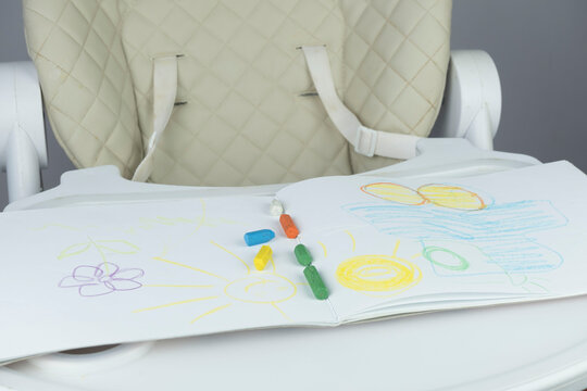white children's chair with a table with an album of drawings and pencils. Children's drawing table.