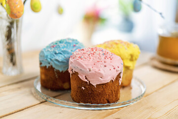 Sweet Easter cakes with colorful eggs on the table in the room.