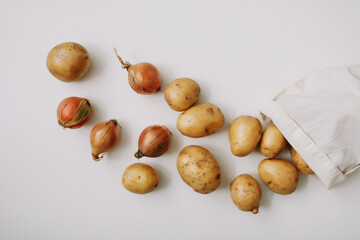 Potatoes and onion in eco-bag on white. organic healthy food background. Flat lay, top view, copy space. Grocery shopping food supermarket and zero waste concept