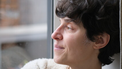 jeune femme brune rêveuse regardant par la fenêtre