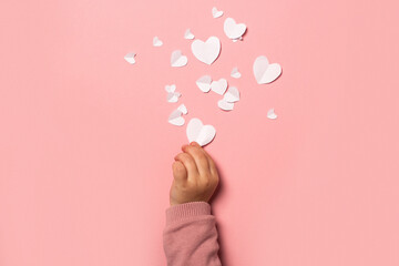 Child's hand takes a valentine card from paper on a pink background. Composition Valentine's Day. Banner. Flat lay, top view