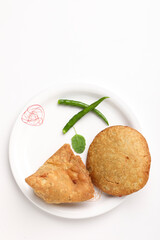 Kachori and potato samosa with green chilly in plate. famous spicy snack in india