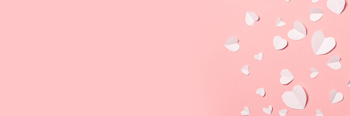 White hearts cut from paper on a pink background. Composition of Valentine's Day. Banner. Flat lay, top view