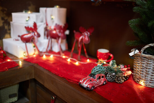 Winter Christmas theme: red toy car with a spruce tree on a yellow garland lights background