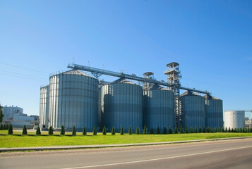 Fototapeta na wymiar Granary. Modern agro-processing plant for the storage and processing of grain crops. Large metal barrels of grain. Horizontal image.