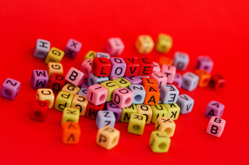 Colorful wooden cube beads with letters on red festive background, word "love". Valentine Day. 14 of February. Flat lay, top view.