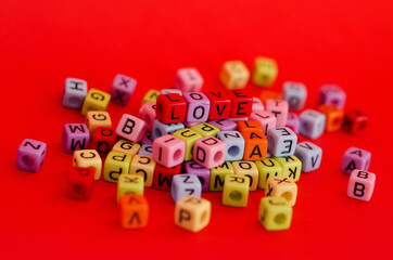Colorful wooden cube beads with letters on red festive background, word "love". Valentine Day. 14 of February. Flat lay, top view.