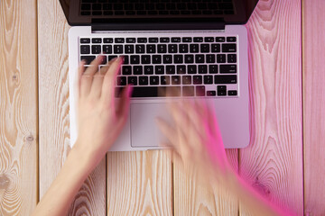 Image of woman’s hands typing fast on laptop keyboard. View from above. Remote work concept image.